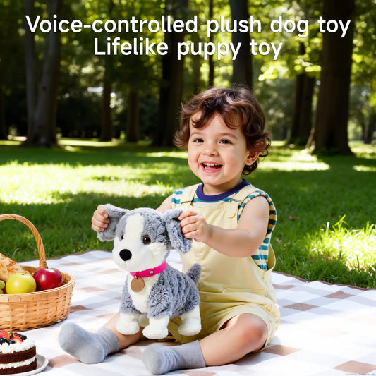 Smiling toddler sitting on a picnic blanket in a park, holding a gray and white voice-controlled plush puppy toy with pink collar, with picnic basket and fruit beside them under green trees