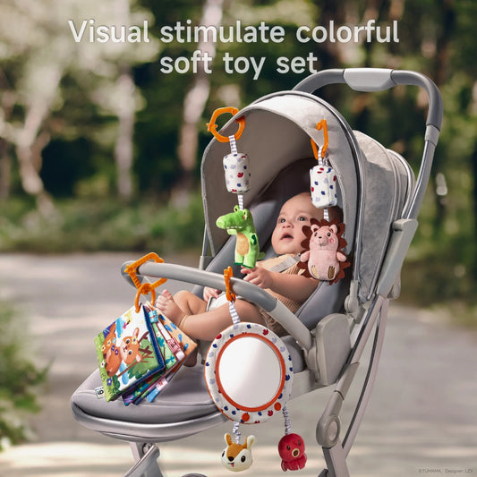 A baby sitting in a stroller engaged with a colorful hanging soft toy set, including a plush alligator, hedgehog, baby-safe mirror with bunny and octopus toys, and a fabric baby book, all clipped to the stroller handle with orange hooks for visual stimulation.