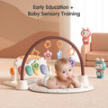 Baby lying on a giraffe-themed play mat under a soft arch with hanging toys, engaging in early education and sensory training activities, with colorful cartoon characters and soft furniture in the background.