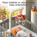 A baby lying in a crib watching a musical mobile featuring a red crab and plush sea animals. The mobile is attached to the crib rail and plays lullabies or soothing sounds to keep the baby entertained and calm. Bright, cheerful nursery décor surrounds the crib.