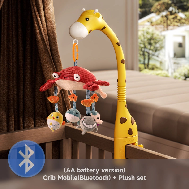 Giraffe-shaped crib mobile featuring a red crab plush with hanging sea animal toys, mounted on a wooden crib. The mobile includes Bluetooth functionality and is powered by AA batteries. A label at the bottom highlights: “Crib Mobile (Bluetooth) + Plush set (AA battery version)” with a Bluetooth icon.