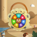 Sheep-shaped baby musical drum toy with colorful light-up buttons displayed in a playful cartoon-style background with mountains, clouds, water, and animal characters. The toy features a portable handle and glowing music keys, designed for interactive fun and entertainment.