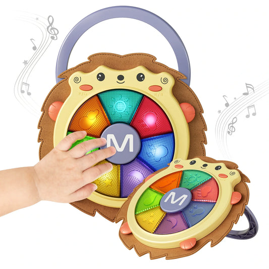 Hedgehog-shaped baby musical drum toy with a carry handle, featuring colorful light-up buttons in rainbow colors. A child’s hand is shown pressing one of the glowing keys, while musical notes float around, highlighting the toy’s interactive sound and light features.