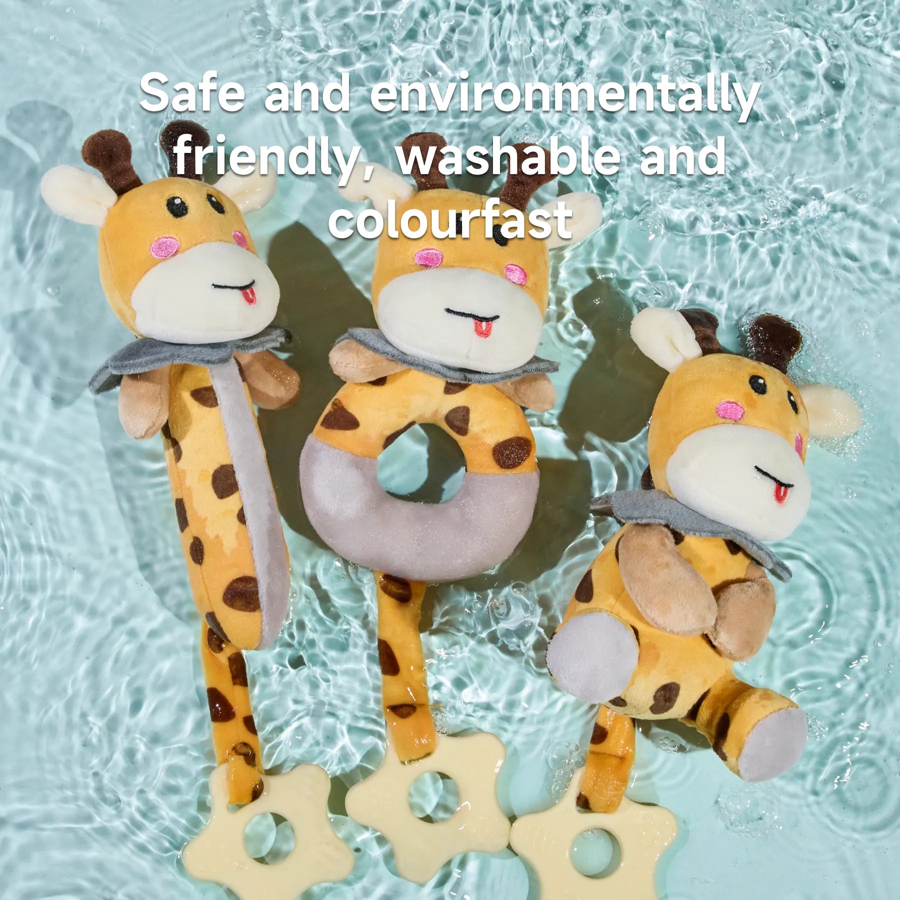 Three plush giraffe rattle toys with star-shaped teether handles placed on a surface with rippling water. The text reads: “Safe and environmentally friendly, washable and colourfast.”