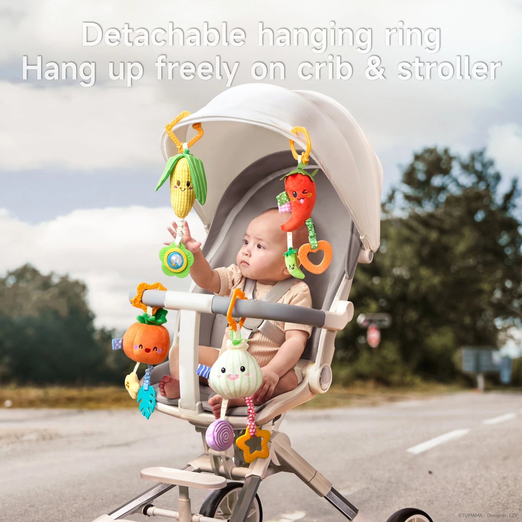 Baby sitting in a stroller with detachable hanging plush vegetable toys—corn, pumpkin, onion, and chili pepper—attached to the canopy and handlebar, showing they can be hung freely on crib or stroller.