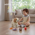 Young child sitting on the floor indoors, reaching toward a battery-operated toy dog as it walks and ‘barks,’ with its colorful accessories (rope ball, remote, toy bottle, bone in bowl) scattered around, overlaid with text ‘Walk and sing adding variety to playtime’ and musical notes.