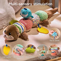 Detailed product showcase of a multi-sensory otter toy displayed on a beige surface against a soft knitted background. The title 'Multi-sensory stimulation' appears at the top. The main image shows the full toy with a cute brown otter head featuring embroidered whiskers and eyes at one end, a tail at the other, and five colorful textured segments in between (striped, pink with circles, multicolored squares, and green dots).