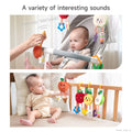 Two scenes show a baby interacting with plush fruit-themed hanging rattle toys. In the top image, a baby sits in a stroller, curiously looking at an adult pressing a plush orange toy that makes a “Bibi” sound. In the bottom image, the baby sits on a soft surface reaching toward the same orange toy, now making a “Sa Sa” crinkle sound. Other plush toys—strawberry, pineapple, and apple—are hanging from a wooden rail. Text overlay reads: “A variety of interesting sounds.”