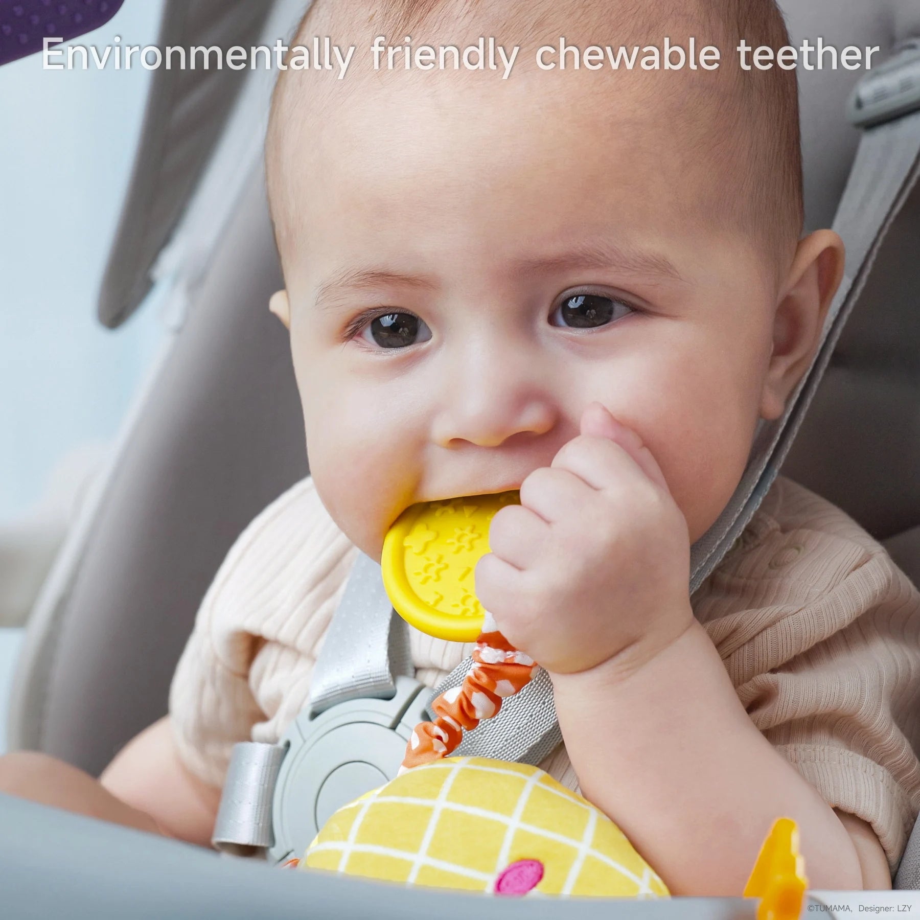 Close-up of a baby sitting in a stroller, chewing on a bright yellow, textured teether attached to a plush pineapple toy. The baby looks content and is securely fastened with a seatbelt. The text overlay reads: “Environmentally friendly chewable teether.”