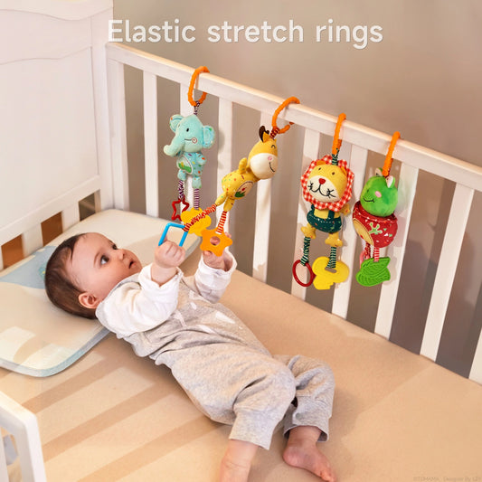 Baby lying in a crib reaching up to grab brightly colored animal plush rattles—elephant, giraffe, lion, and frog—suspended by orange elastic stretch rings from the crib rail.