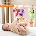 Baby lying in a crib, reaching up with hands and feet to play with three colorful plush marine animal toys—a red lobster, purple octopus, and green seahorse—hanging from the crib rail. The text overlay reads: 