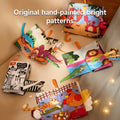 Colorful baby cloth books laid open to reveal original hand-painted animal illustrations and textured tails. Themes include dinosaurs, sea creatures, jungle animals, farm animals, and black-and-white high-contrast animals. Each book features bright, eye-catching patterns and soft fabric tails.