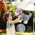 Child joyfully lifting a soft gray and white plush puppy toy under a sun umbrella, showcasing its short, safe-touch fur and durable build with sturdy internal mechanics
