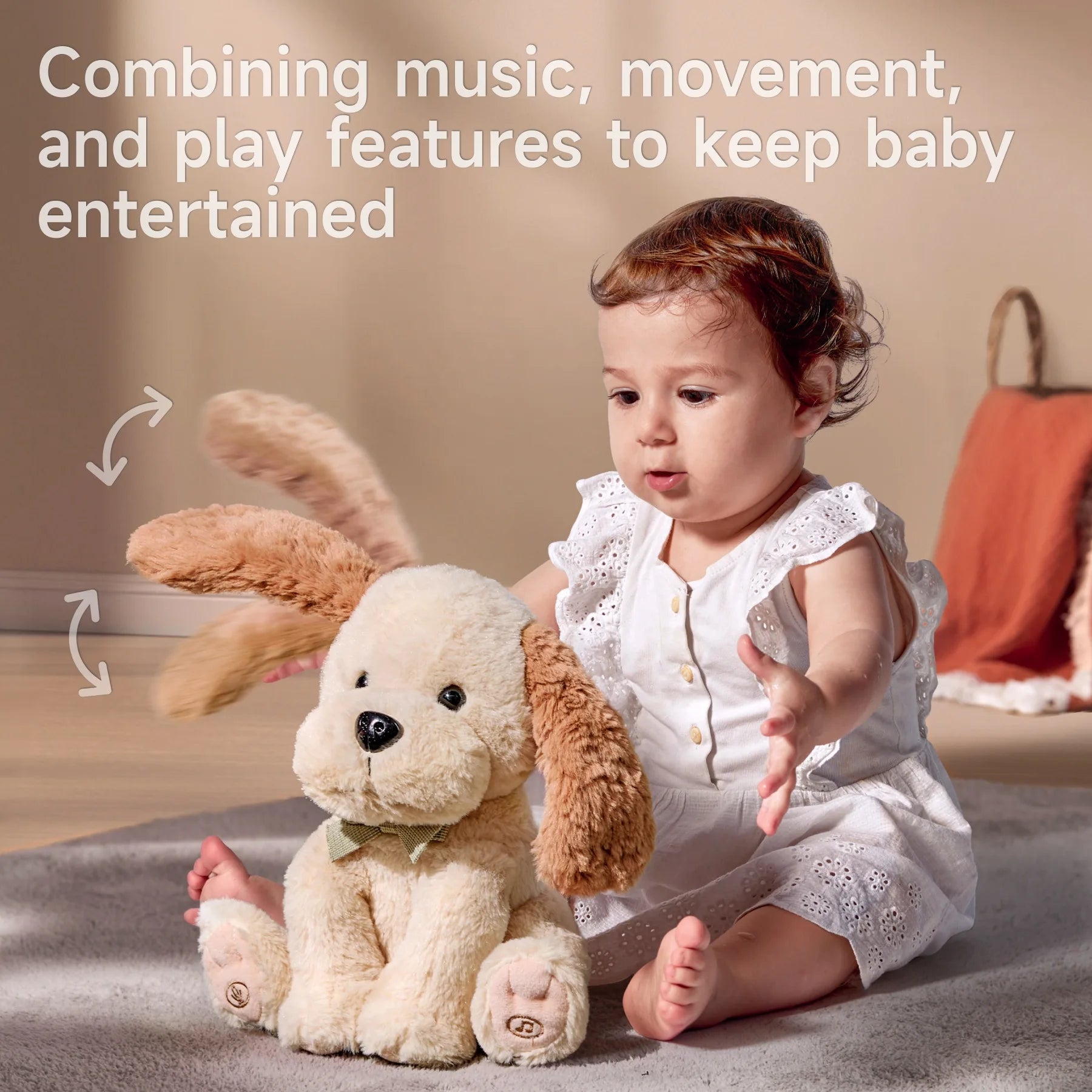 Smiling baby in a white eyelet dress sitting on a soft rug, interacting with a plush beige dog toy with floppy brown ears and a green bow tie. The toy’s ears are shown flapping with motion arrows. Text above reads: 'Combining music, movement, and play features to keep baby entertained'.