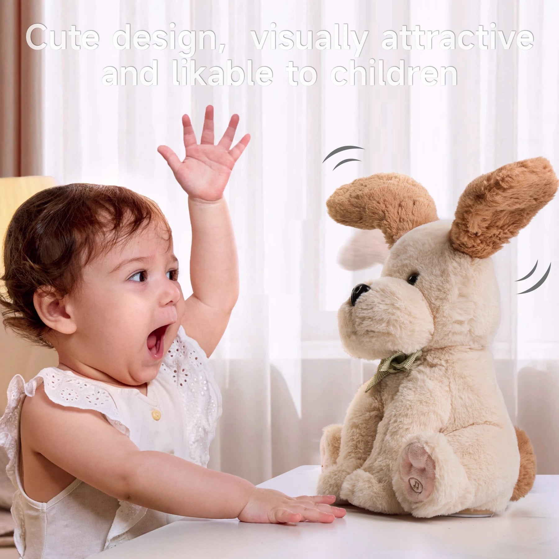 Excited baby raising one hand in delight while interacting with a plush beige dog toy with brown floppy ears and a green bow tie. The toy’s ears are shown mid-motion, suggesting interactivity. Background features sheer white curtains. Text above reads: 'Cute design, visually attractive and likable to children'.