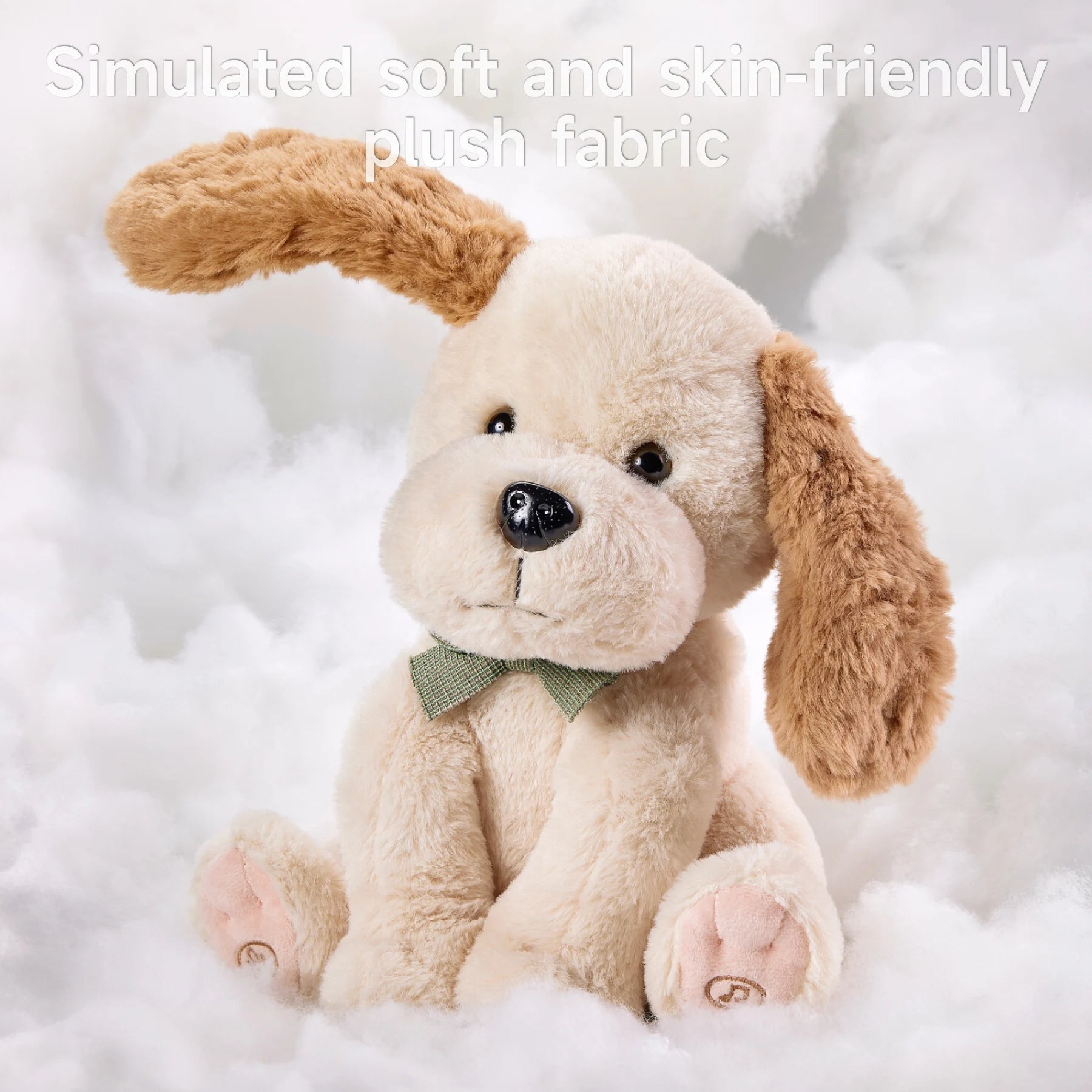 Beige interactive stuffed animal dog toy with soft, fluffy fur and brown floppy ears, sitting upright in a cloud-like white background. The toy features a green bow tie and embroidered paws. Text above reads: 'Simulated soft and skin-friendly plush fabric'.
