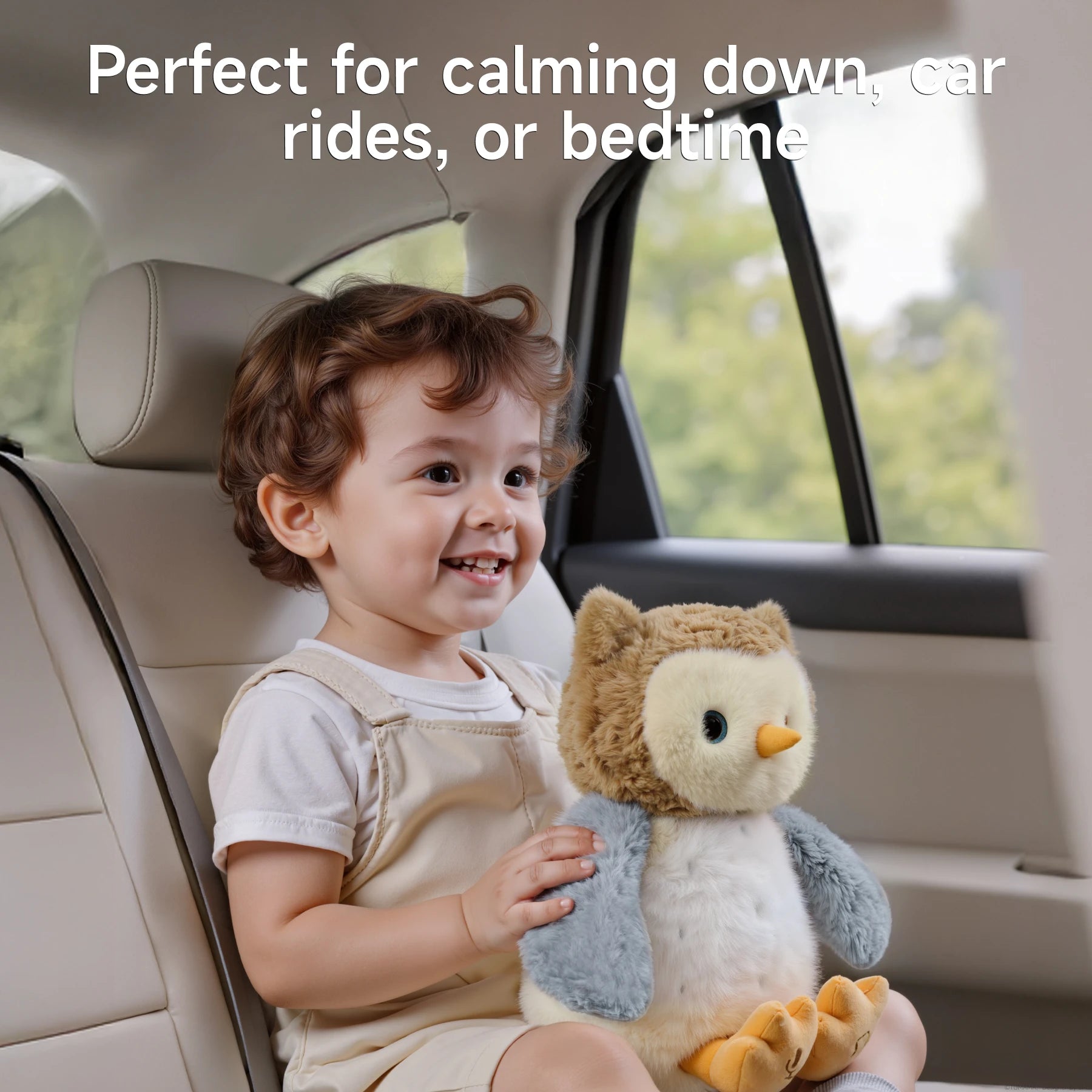 Smiling toddler sitting in a car seat holding an interactive owl plush toy with soft brown and gray fur. Text at the top reads: "Perfect for calming down, car rides, or bedtime," highlighting the toy's soothing and comforting qualities.