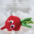 Close-up of a soft red plush beet toy with green leaves and embroidered facial features, nestled in fluffy white polyester filling. Text overlay reads: 'Exquisite embroidered and stitched craft. Fully filled with polyester'.