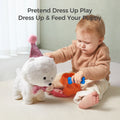 Toddler playing with a white interactive toy dog wearing a glittery pink party hat and bow tie. The child is pretending to feed the puppy using a blue bone-shaped toy and orange feeding bowl. Pretend play activity encourages imagination.