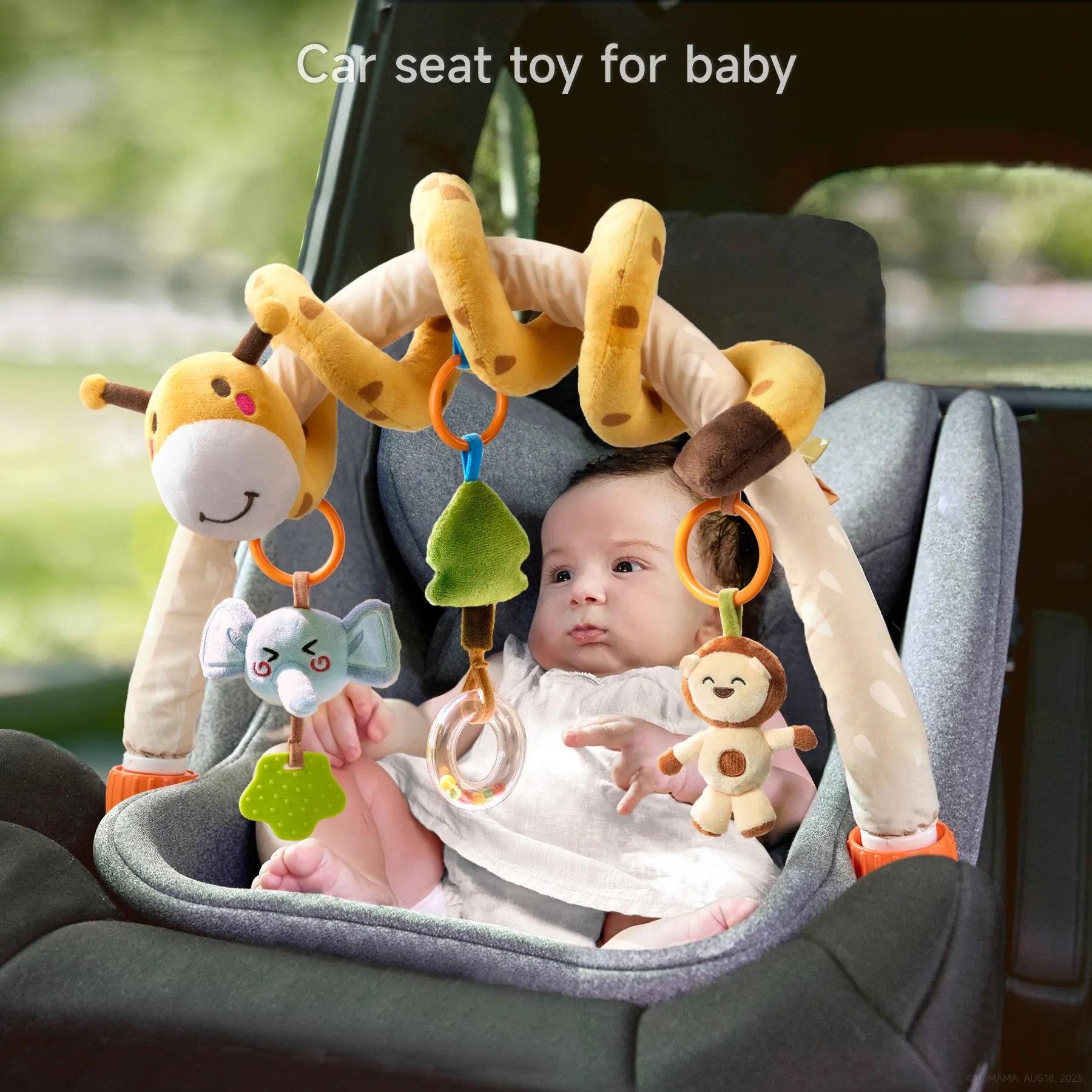 Baby sitting in a car seat playing with a giraffe arch toy attached to the seat. The arch has plush hanging toys including an elephant teether, green tree rattle, clear bead ring, and smiling monkey. Text overlay says, “Car seat toy for baby.”