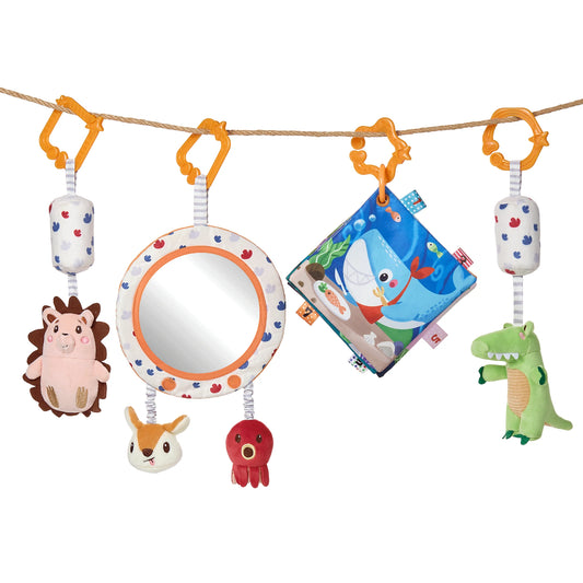 A colorful baby sensory toy set hanging from a rope, featuring a plush hedgehog, a soft mirror, a red octopus, a bunny head, a fabric baby book with ocean animals, and a green alligator plush, each suspended with patterned fabric straps and orange hooks.