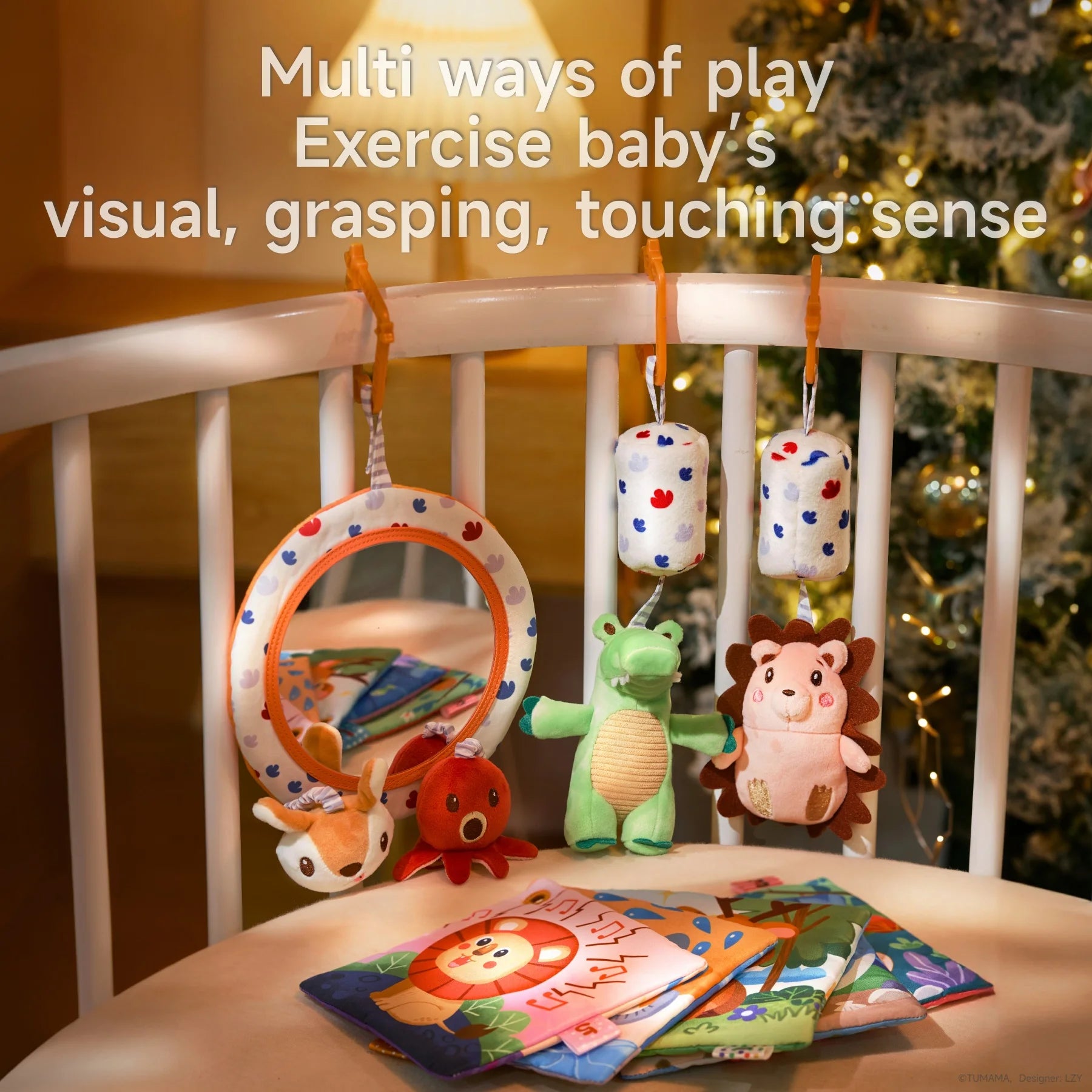 A variety of colorful baby toys including a soft mirror with plush animals, a green alligator, a pink hedgehog, and hanging cylindrical rattles attached to a crib rail. Several baby cloth books are spread out on the mattress, emphasizing play that supports visual, grasping, and touching development.