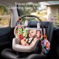A baby seated in a car seat interacts with a colorful soft toy set hanging from an arch. The toy set includes a mirror, plush animals (crocodile, hedgehog, bunny, octopus), cylindrical rattles, and fabric books, designed to soothe and entertain during travel.