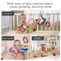 A collage of three scenes showing a baby playing with a colorful soft toy set in a crib. The top image shows the baby seated with various hanging plush toys, a mirror, and cloth books; text overlays read “Draw attention” and “Multi ways of play, exercise baby’s visual, grasping, touching sense.” The bottom left shows the baby engaging with cloth books labeled “Improve recognition.” The bottom right shows the baby on their tummy looking at their reflection in the mirror labeled “Recognize facial features.”
