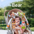 A baby sitting in a stroller, smiling and playing with a bear-themed arch toy. The toy features a plush bear, deer, mushroom, pineapple teether, and bead rattle, securely attached to the stroller for interactive fun.