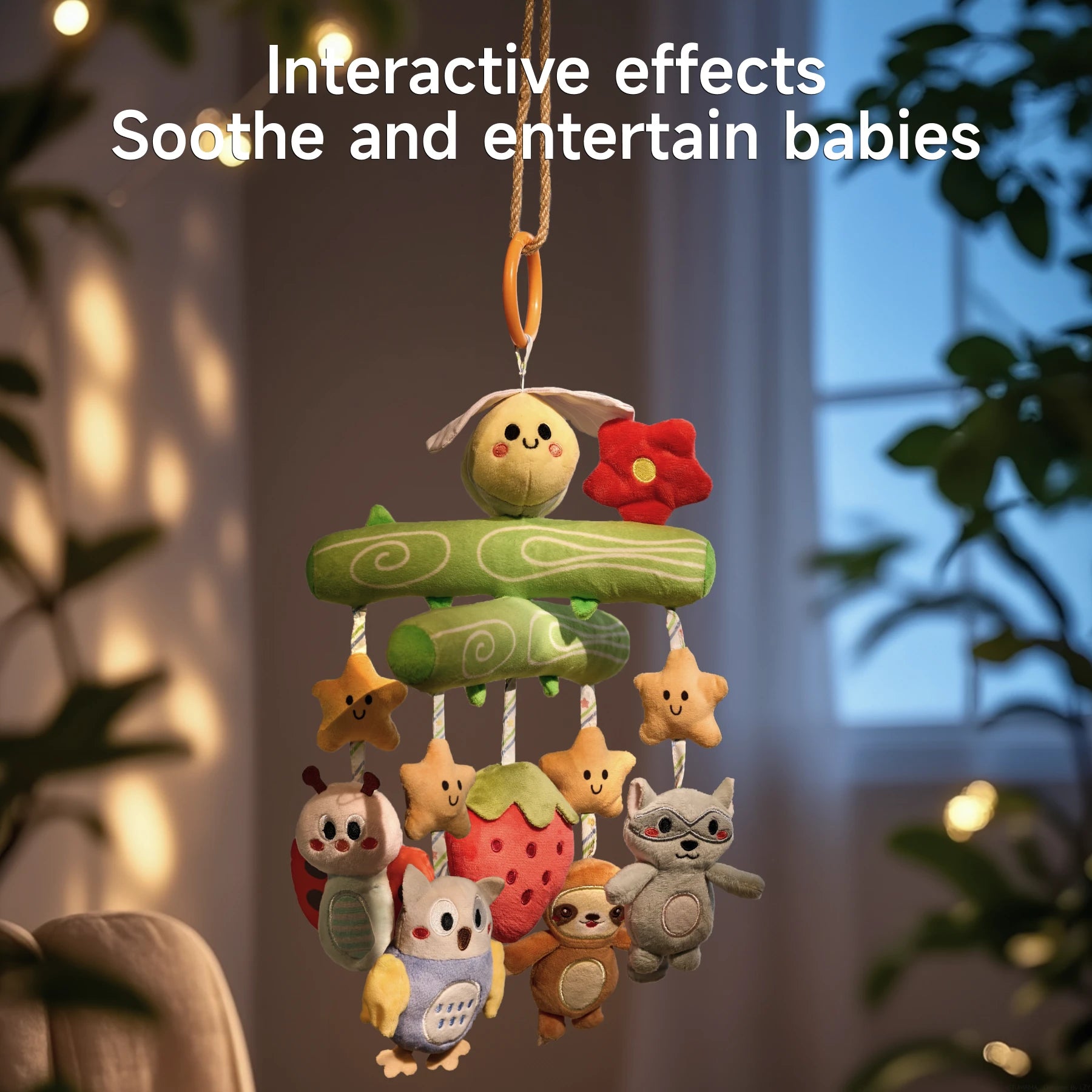 A close-up of a Woodland Animal Crib Mobile hanging indoors in a softly lit room. The mobile features a green tree branch design with a yellow bee and red flower at the top, and plush toys including stars, a ladybug, an owl, a strawberry, a sloth, and a raccoon. The background is cozy with blurred plants and window, and text over the image reads, "Interactive effects Soothe and entertain babies."