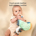 Baby lying on a soft surface, holding and chewing on the food-grade teether attached to a zebra baby security blanket, with the text 