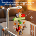 An interactive crib mobile featuring plush toys like a ladybug, owl, raccoon, sloth, and stars. Shake the bee for jingling sounds, and squeeze the star for BB sounds. The mobile is attached to a crib, playing music and rotating gently.